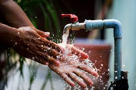 A person washing their hands with water from a spout